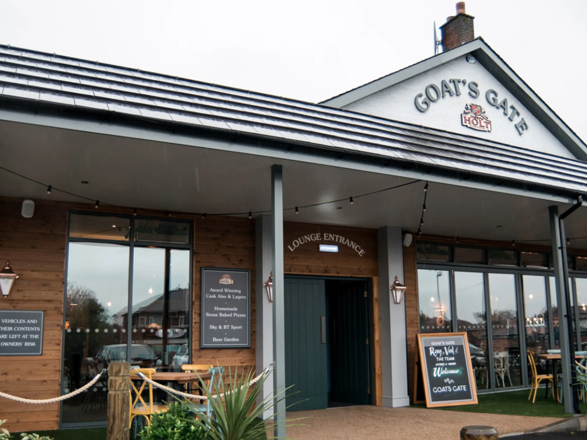 The front of the Goat's Gate with its covered terrace and gable sign at Goats Gate, a pub in Whitefield