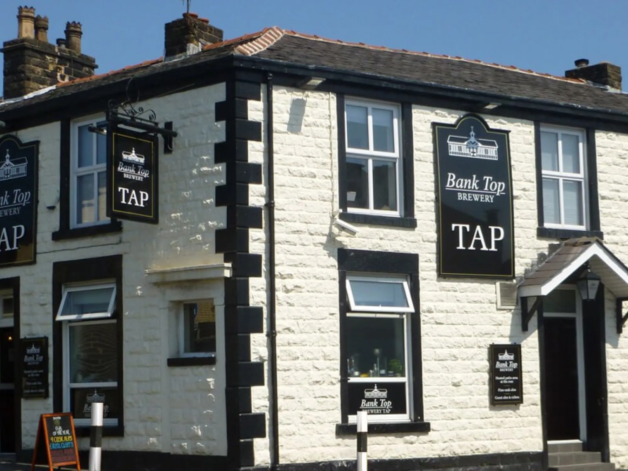 The white painted corner front of the Bank Top Brewery Tap on Belmont Road with its Tap signs, a brewery taproom in Bolton