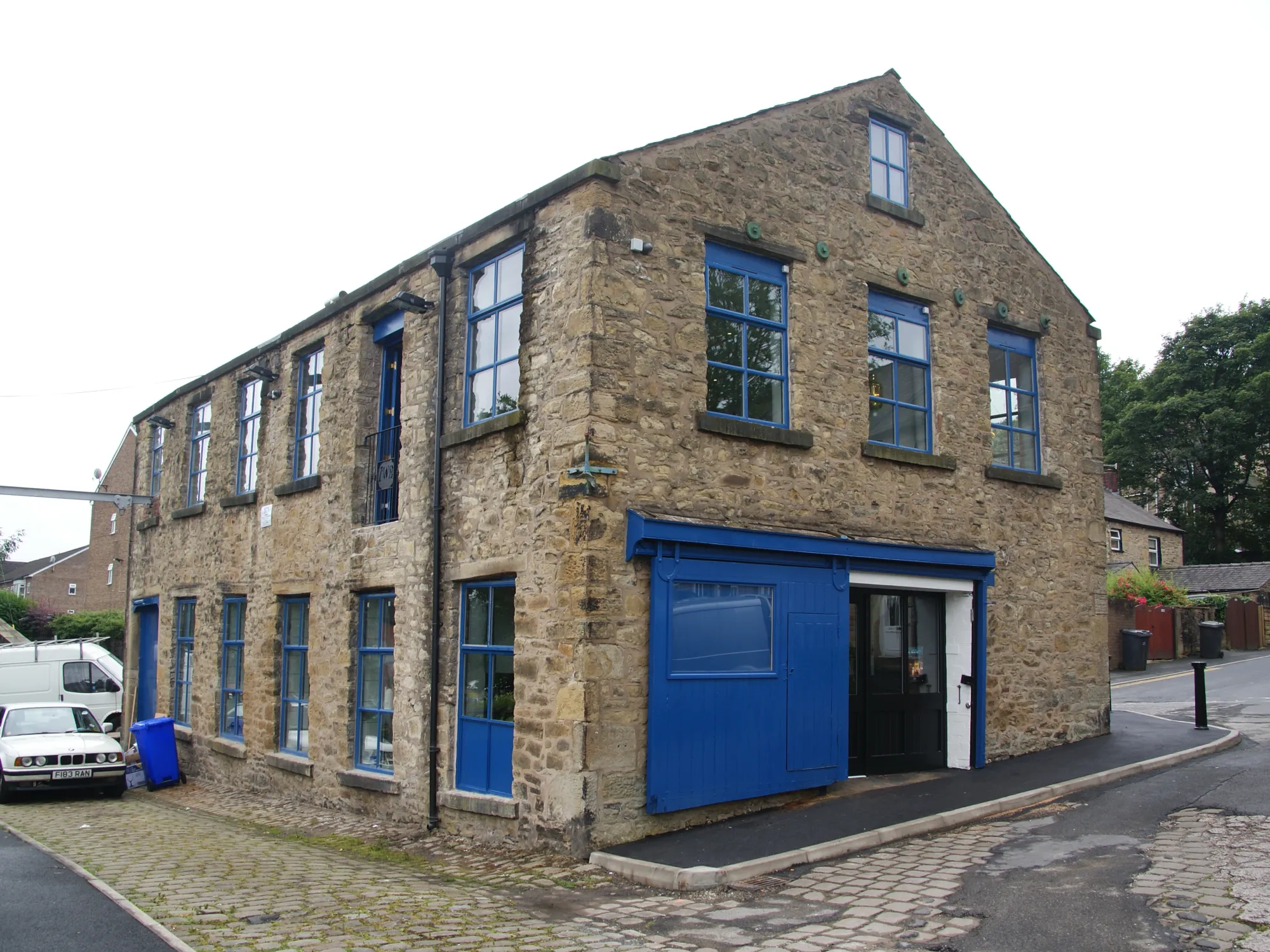 The stone mill building of Irwell Works Brewery on Irwell Street with its blue doors, a brewery taproom in Ramsbottom