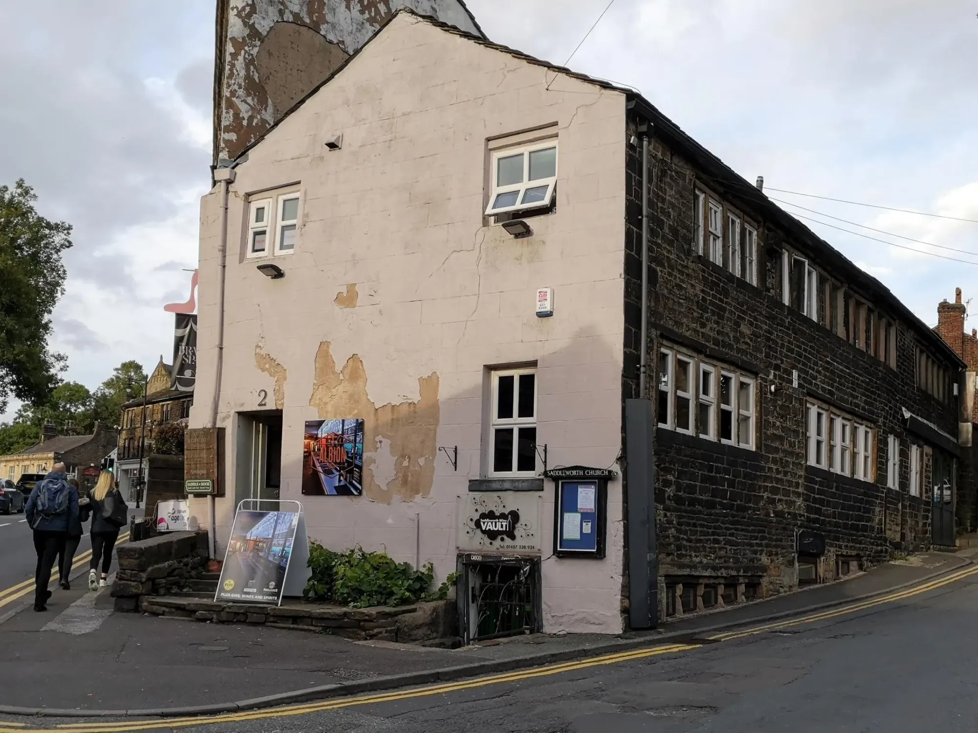 The cream-rendered end of the stone terrace on High Street, Uppermill, with an Albion sign by the doorway at Albion Tap, a craft beer bar in Uppermill