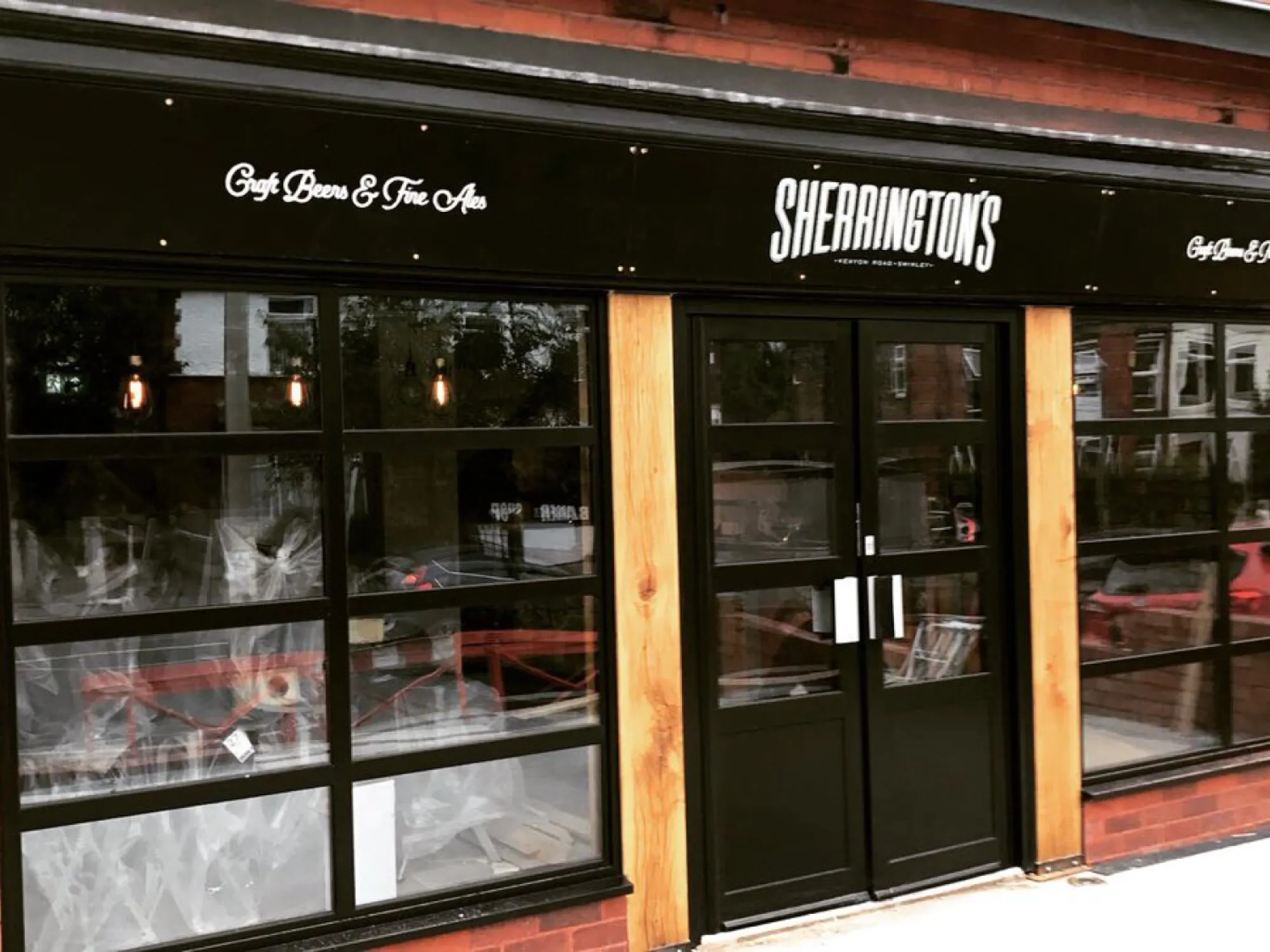 The black Sherrington's fascia and glazed shopfront at 57 Kenyon Road at Sherringtons, a craft beer bar in Wigan