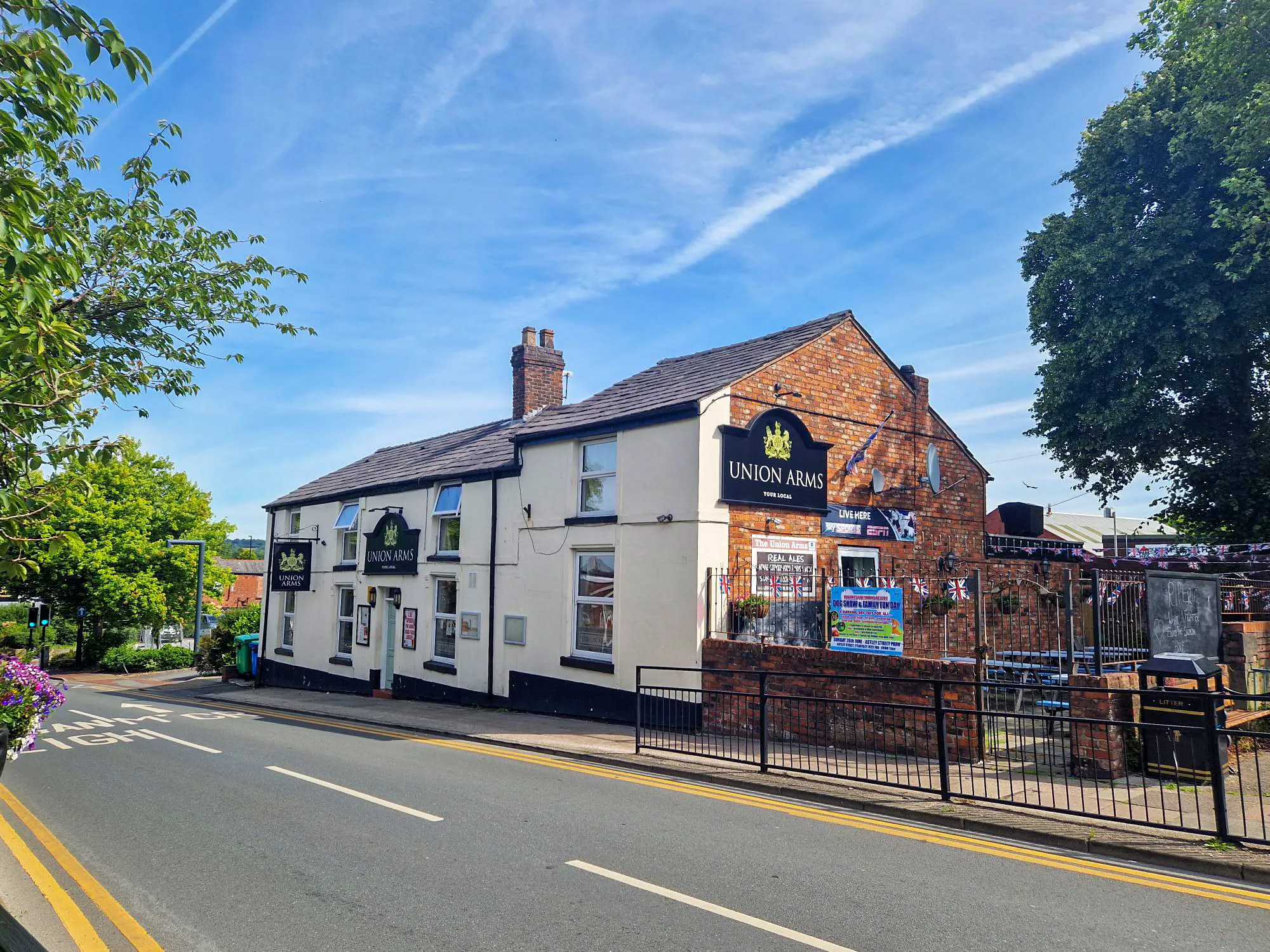 The cream-painted front of the pub on Castle Street, with its signs and the brick-walled beer garden beside it at Union Arms, a pub in Tyldesley