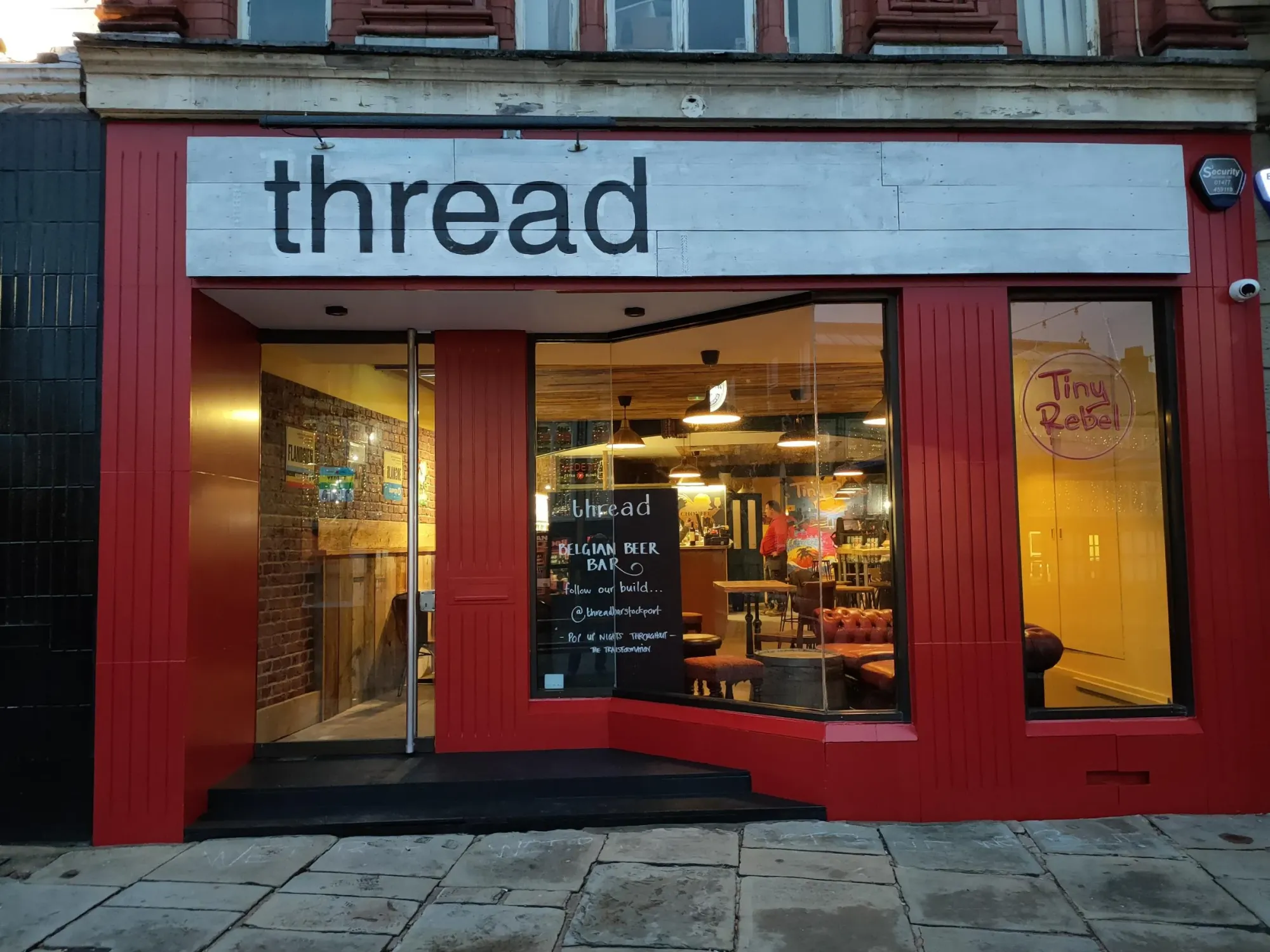 The red shopfront of Thread on Stockport Market Place with its name on the fascia above the open doors, a craft beer bar in Stockport