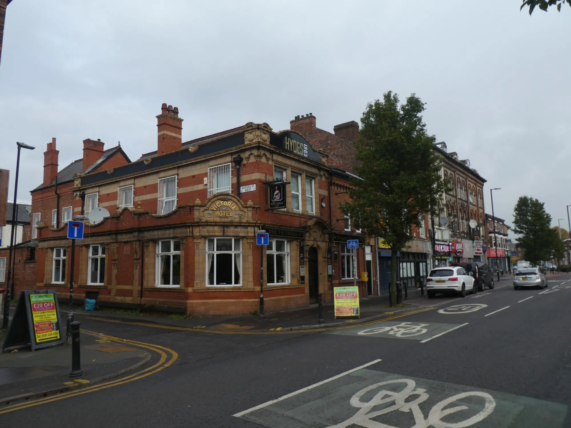 The red brick and terracotta corner front of the Victoria Hotel on Wilmslow Road, with the Hydes sign on the roofline at The Victoria, Withington, a pub in Withington