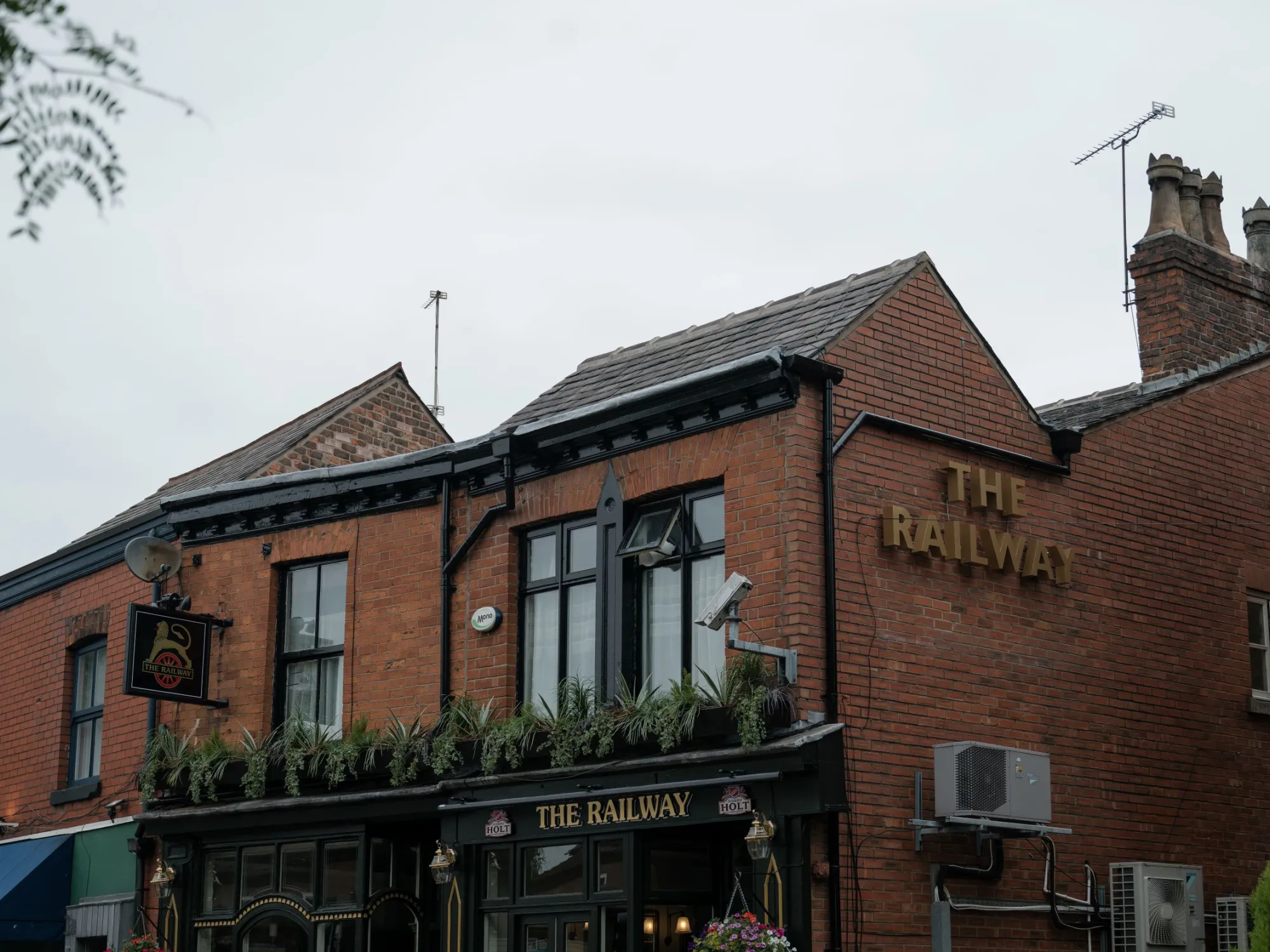 The red brick front of the Railway on Lapwing Lane, with its gold lettering and black fascia at The Railway, West Didsbury, a pub in West Didsbury