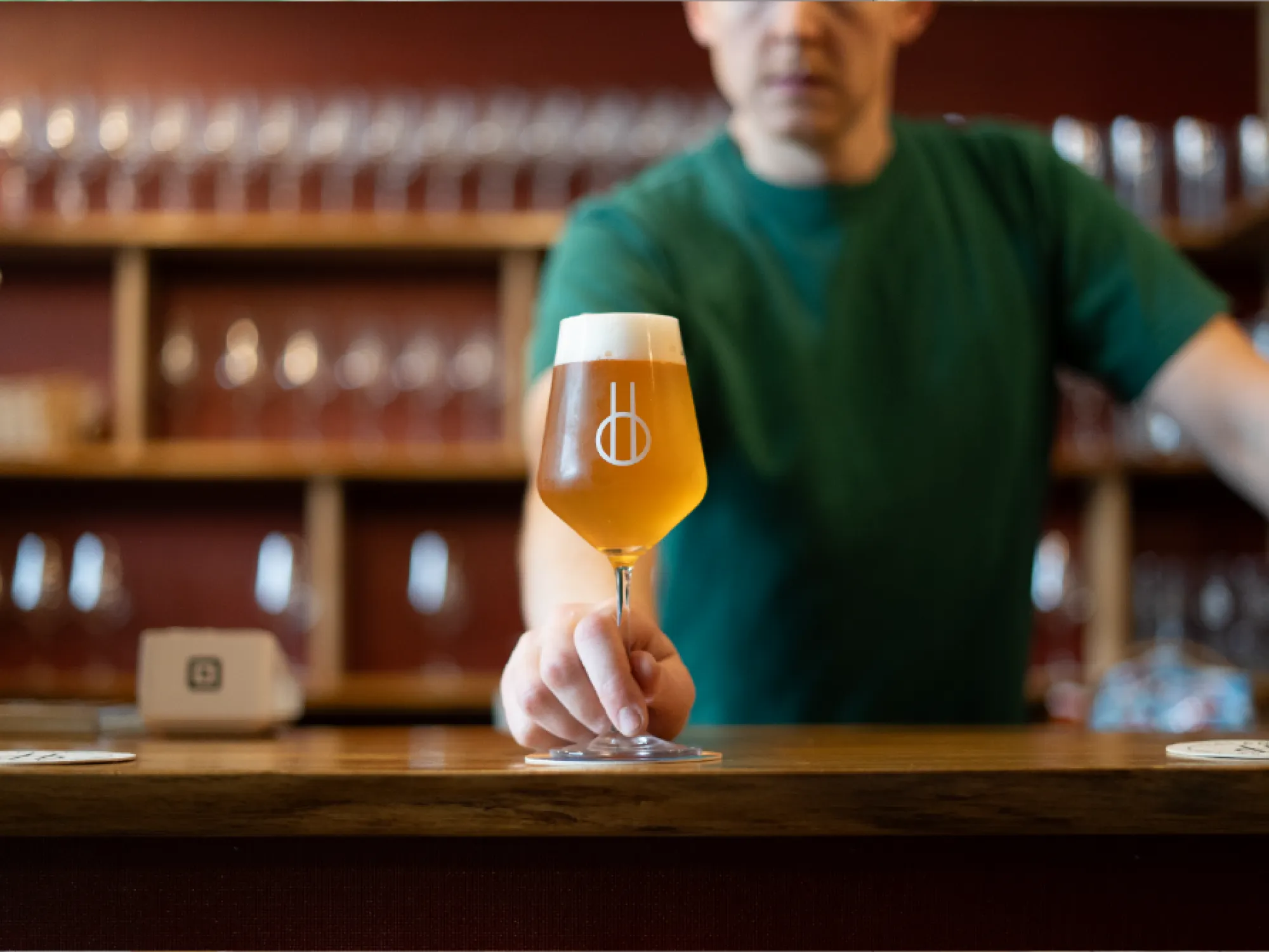 A glass of beer served on the bar at Balance Brewing & Blending, glass shelves behind, a brewery taproom in Piccadilly, Manchester