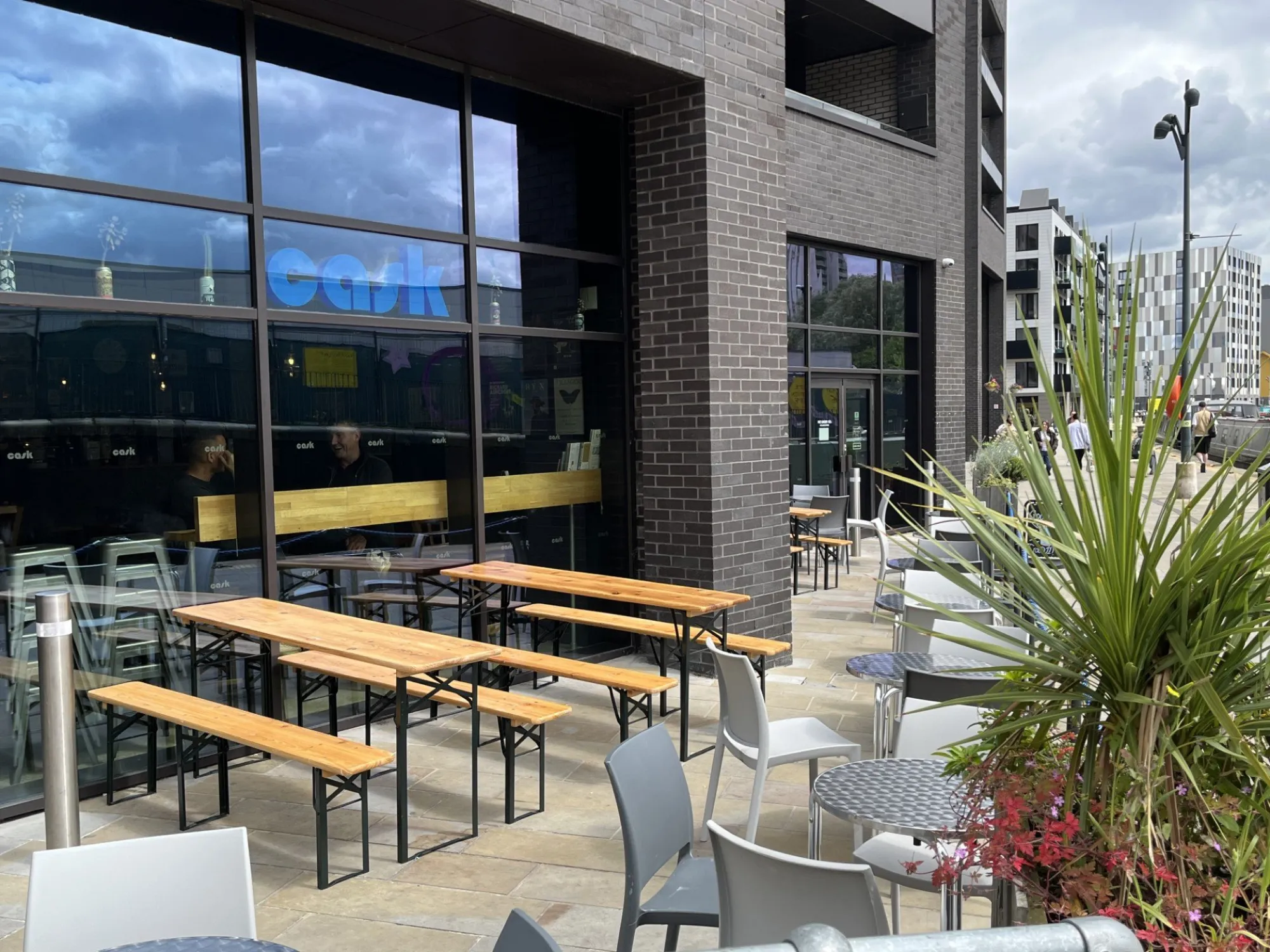 The glass front of Cask Ancoats with picnic benches on the terrace, a craft beer bar in Ancoats, Manchester