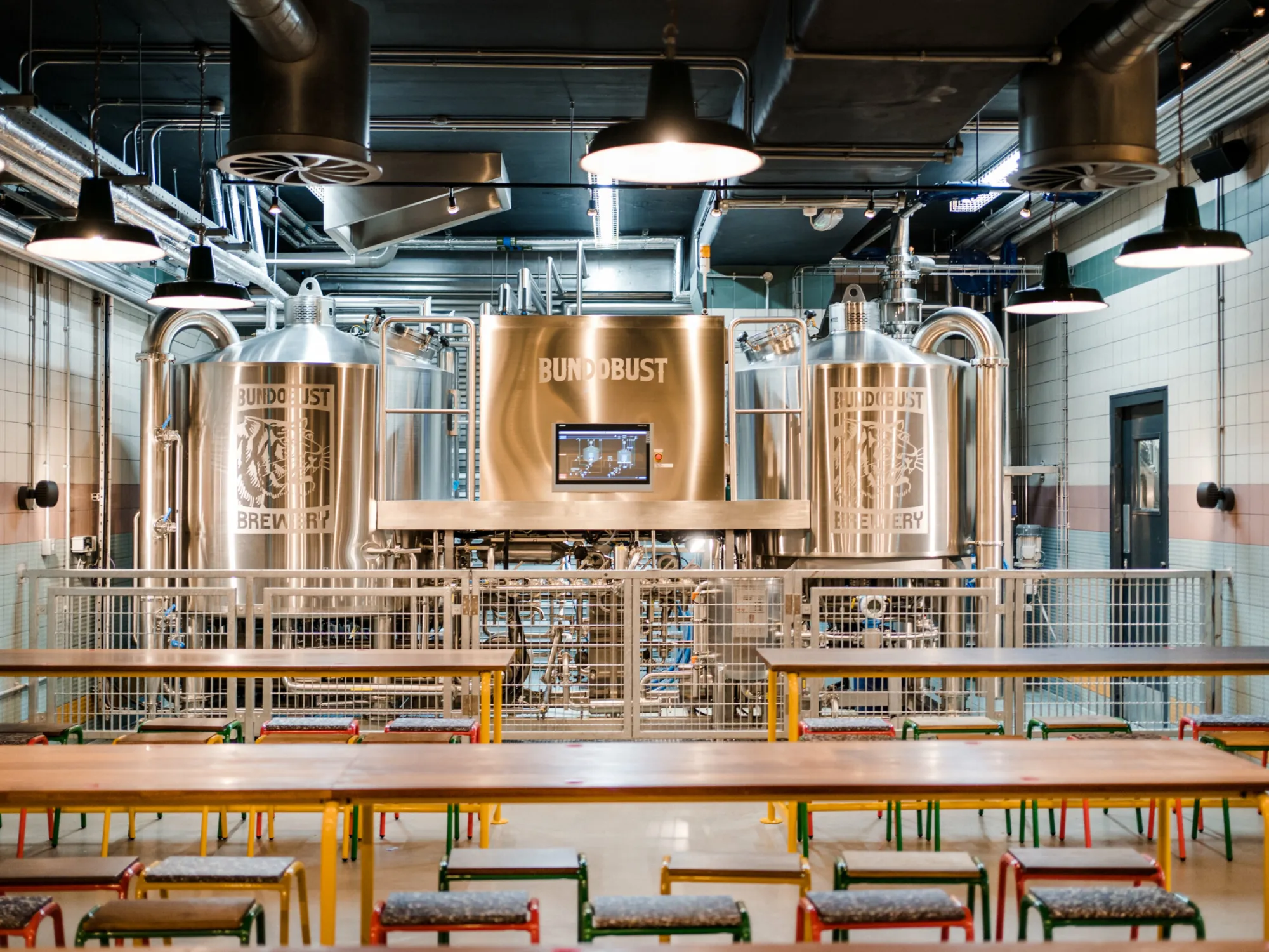 Long tables and stools in front of the Bundobust brewhouse at the Oxford Street brewery at Bundobust Brewery, a brew pub in Oxford Road, Manchester