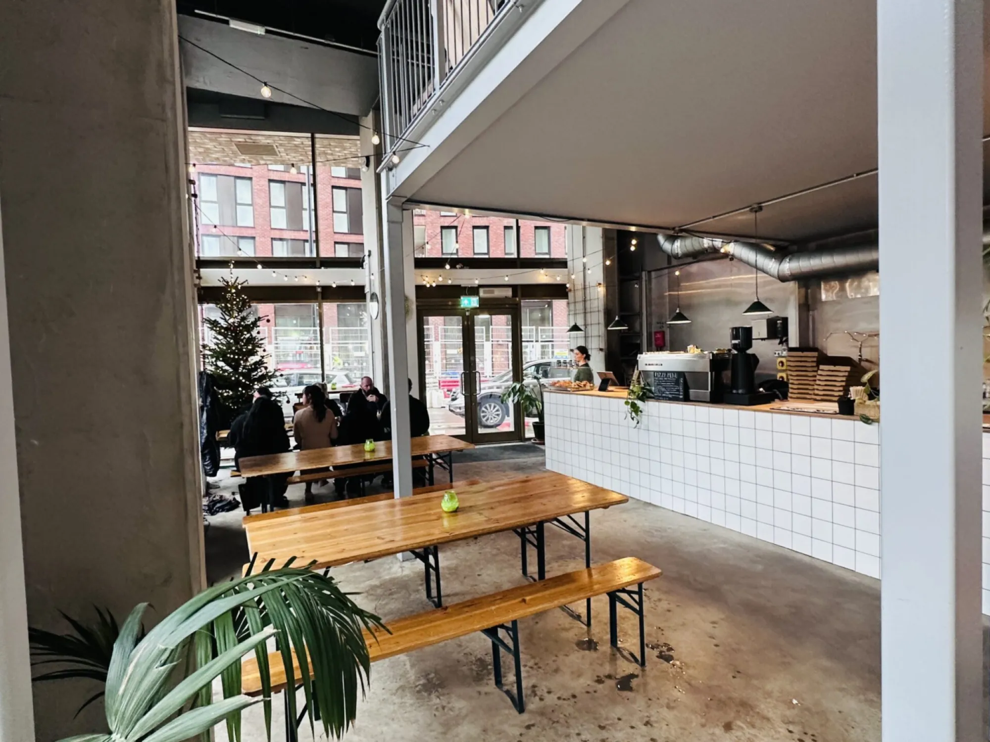 Long wooden tables and the white tiled counter inside Mongrel on Great Ancoats Street, a craft beer bar in Ancoats, Manchester