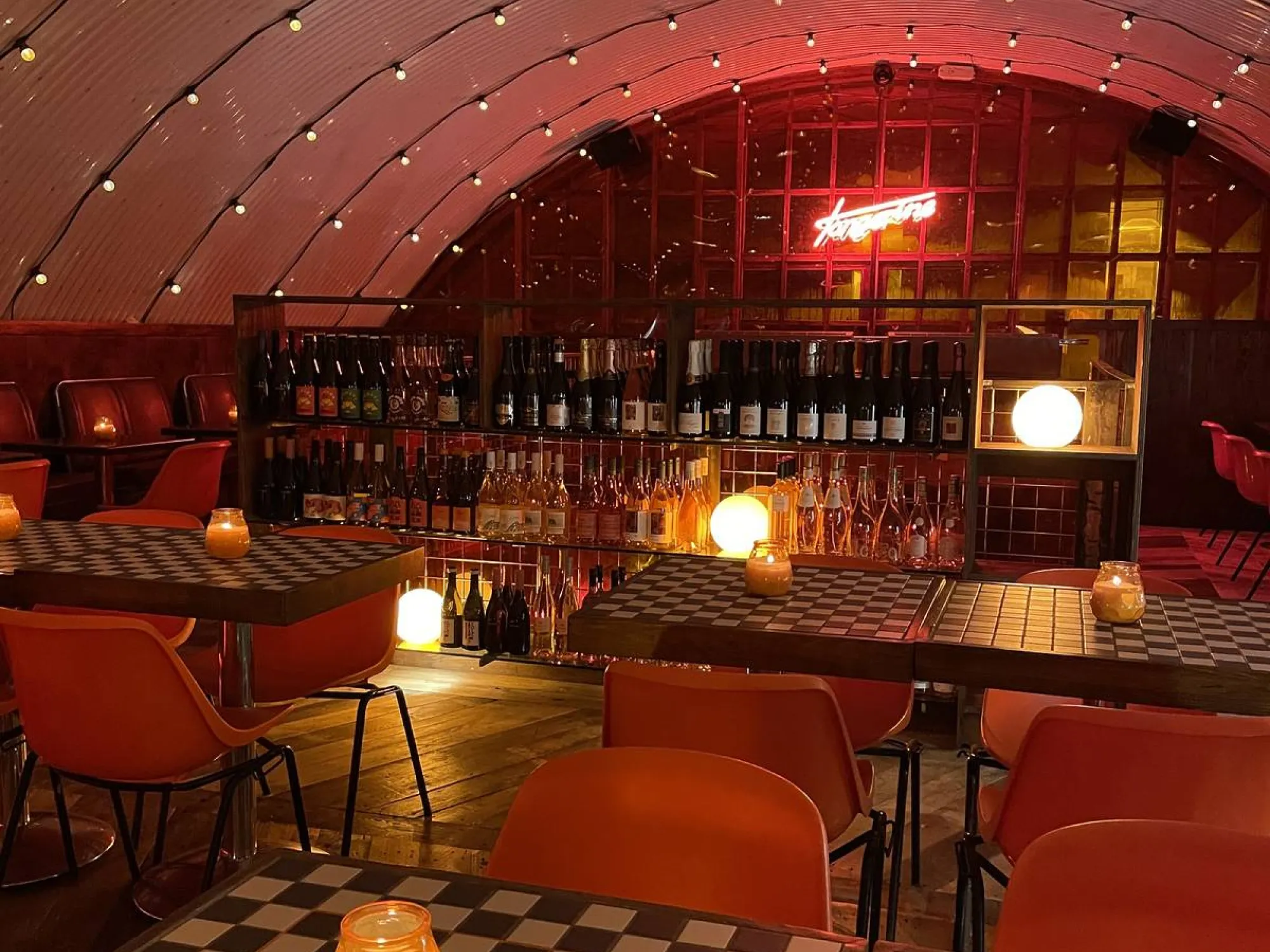 The red lit arched bar at Tangerine, with orange chairs and its neon sign, a street food hall in Salford