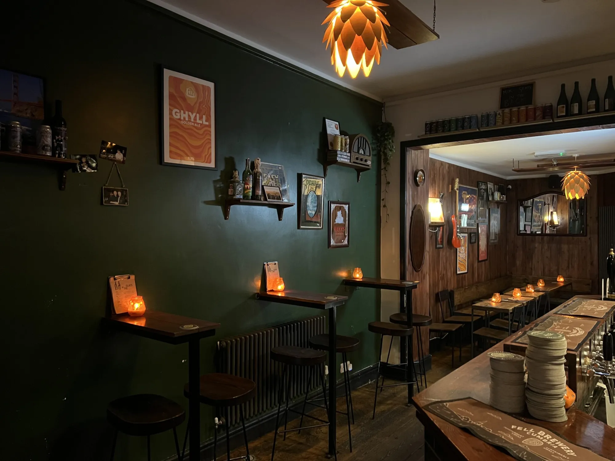 Inside Fell Chorlton at night, with dark green walls, high tables and the bar, a craft beer bar in Chorlton, Manchester