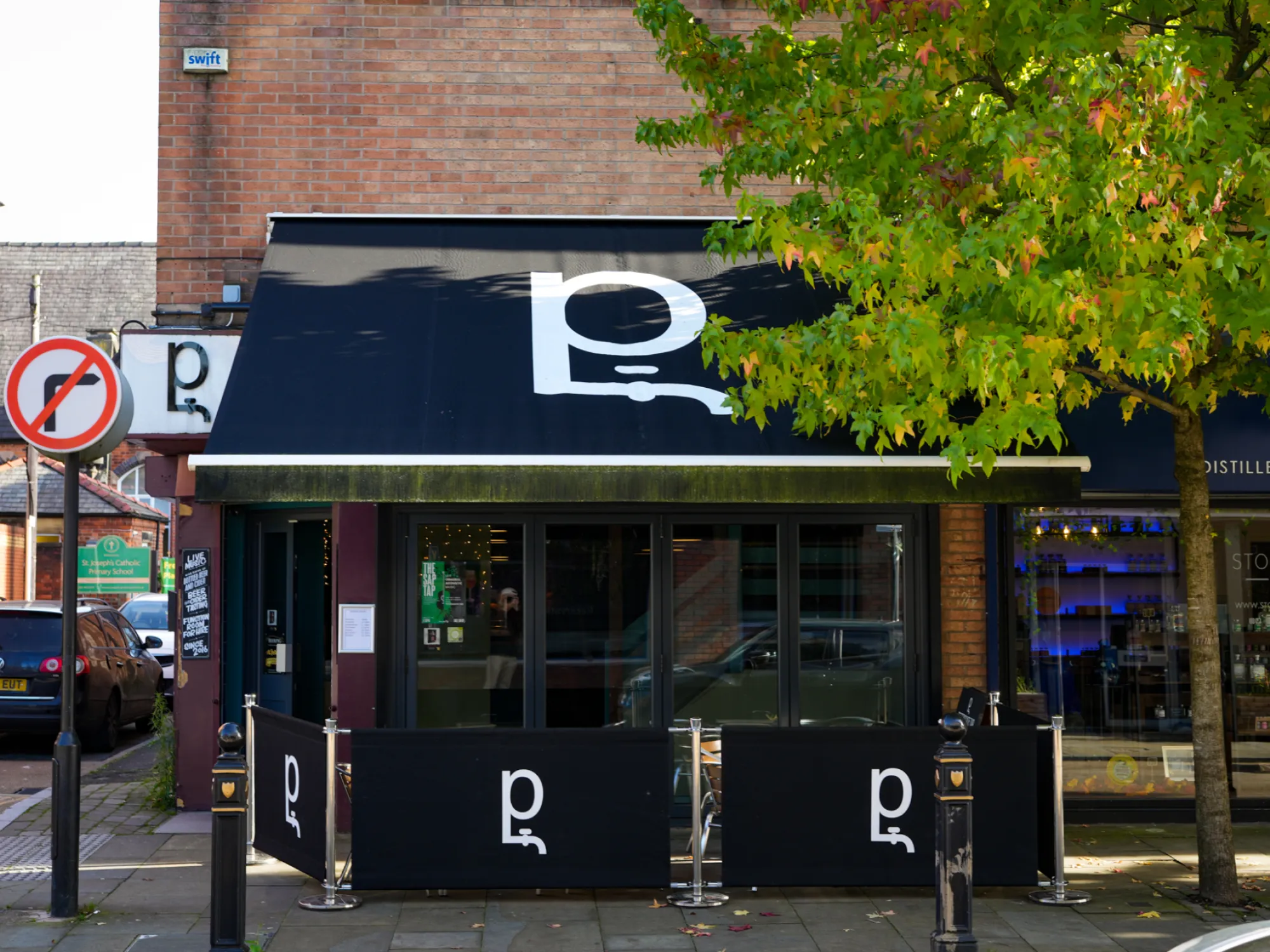 The front of Petersgate Tap on St Petersgate, Stockport, with its black awning and outdoor screens, a craft beer bar in Stockport