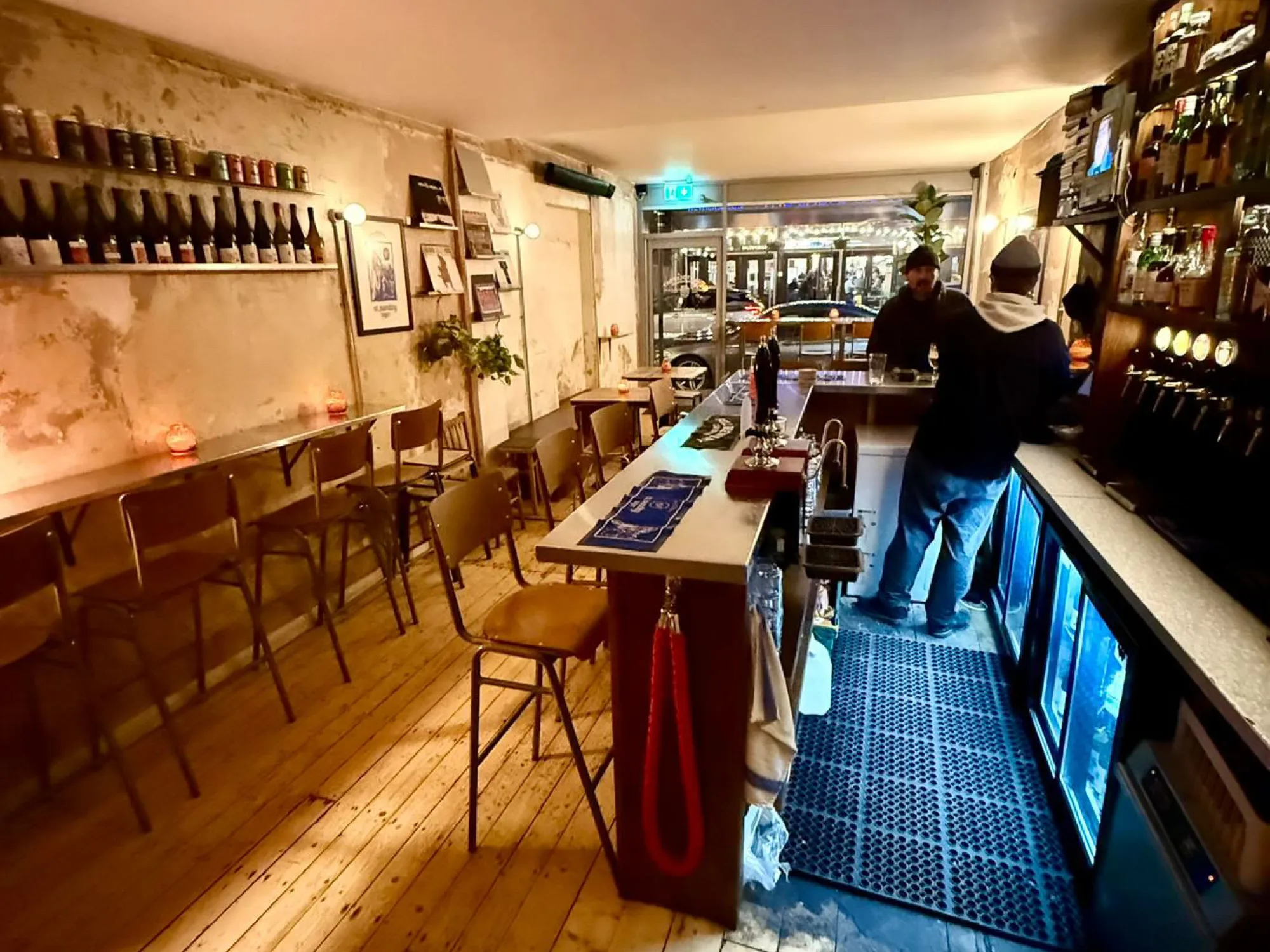 The long bar at Fell Stockport, with stools, bare floorboards and bottles on the back wall, a craft beer bar in Stockport