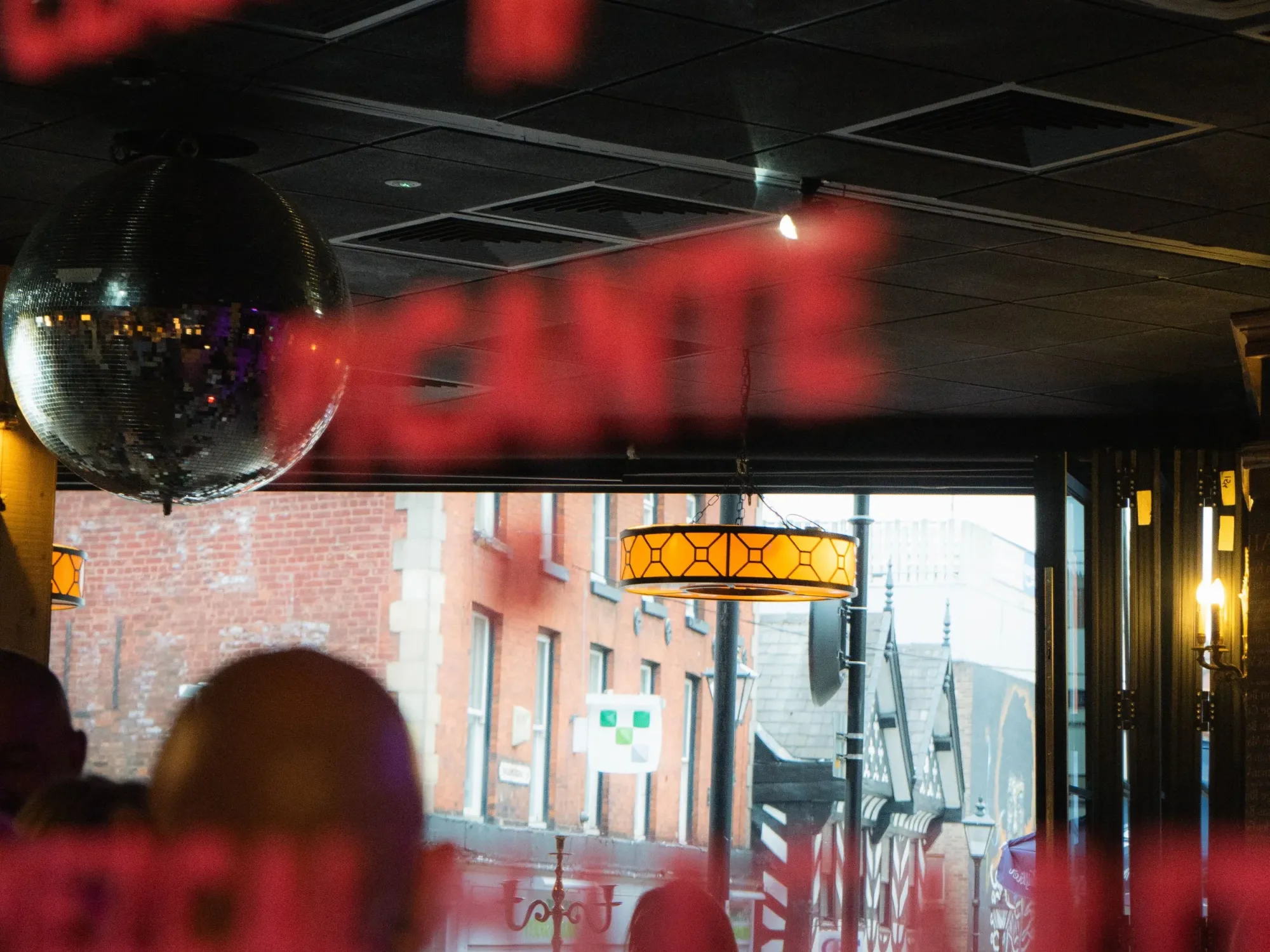 Inside The Underbank, looking out through the windows past its red neon sign, a craft beer bar in Stockport