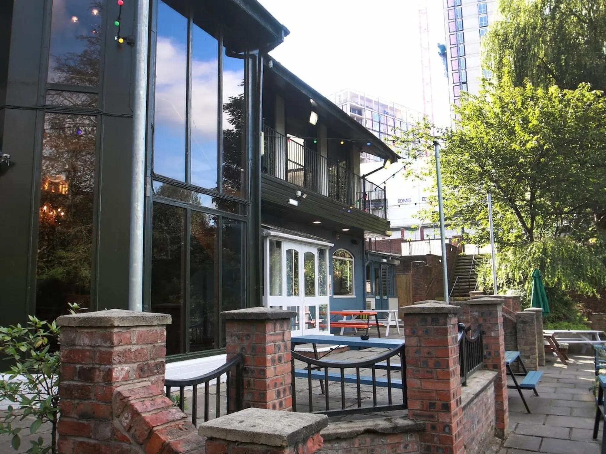 The glazed riverside pub building with its brick-walled terrace and outdoor tables at The Old Pint Pot, a pub in Salford