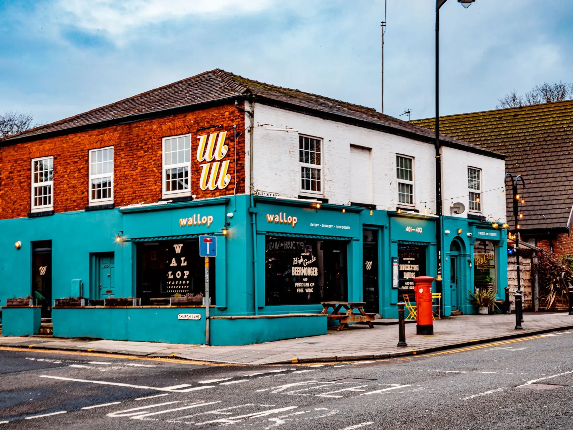 The turquoise corner frontage of Wallop at 401-403 Bury New Road, with its outdoor tables at Wallop Prestwich, a craft beer bar in Prestwich