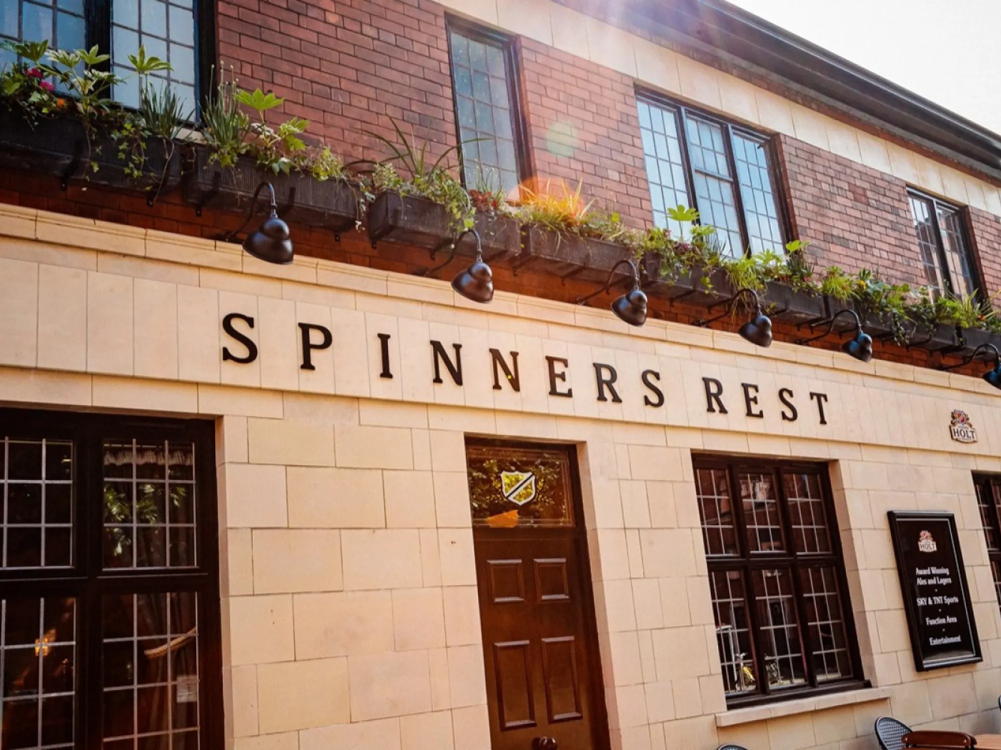 The cream and red brick front of the pub with its Spinners Rest sign on Bengal Street at Spinner's Rest, a pub in Manchester